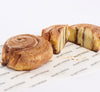 Two gluten free cinnamon buns with one slice cut in half on white background