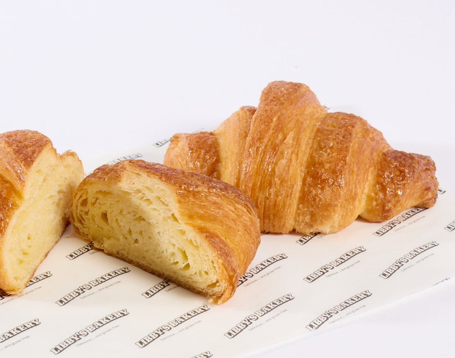 Two gluten free croissants on a white surface on libbys branded paper 